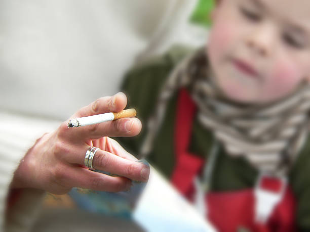 a guy holding cigarette and smoking in front of a baby girl